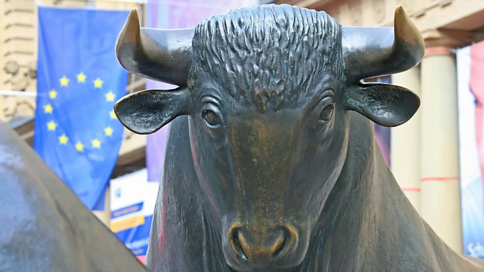 Bronzene Bullen-Skulptur vor einer Europaflagge als Symbol für deutsche Dividendenaktien